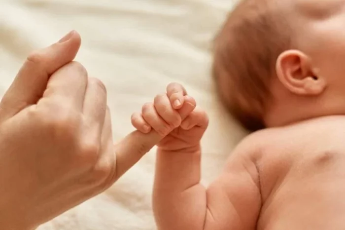 1_mae_sem_rosto_com_bebe_nu_crianca_segurando_o_dedo_da_mamae_mae_passando_um_tempo_com_seu_filho_pequeno_sobre_fundo_claro-27489494