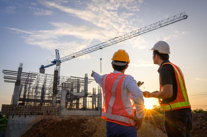 A team of construction engineers talks to managers and construction workers at the construction site. Quality inspection, work plan, home and industrial building design project