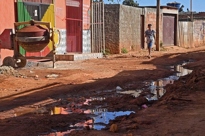 A youngster walks near sewage water in a ditch in a street in Santa Luzia, Guara, 20 km from Brasilia, on August 3, 2020. - Washing hands frequently is one of the main recommendations to prevent the new coronavirus, but in Brazil, where 35 million people lack drinking water, it is not so easy to comply with it. (Photo by EVARISTO SA / AFP)