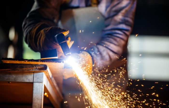 Worker cutting metal with plasma equipment on plant.